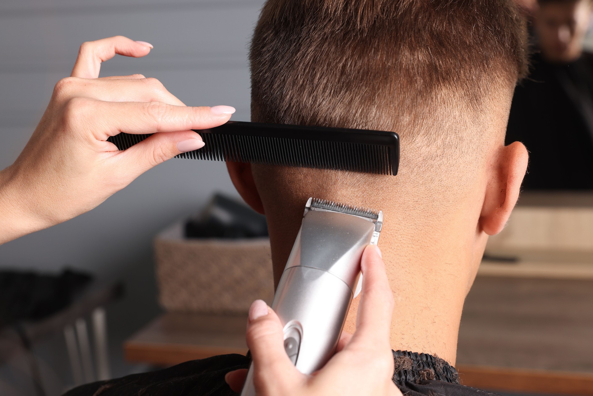 Professional barber making stylish haircut in salon, closeup
